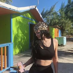 a woman wearing a leopard print headband standing in front of a colorful building