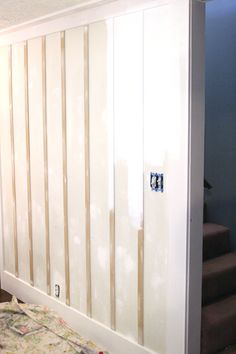 a bedroom with white walls and wooden slats on the wall, next to a bed