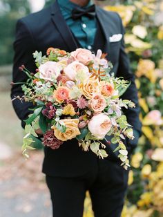 a man in a tuxedo holding a bouquet of flowers on his lapel