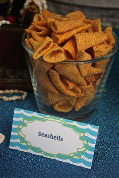 a glass bowl filled with cheetos sitting on top of a blue table cloth