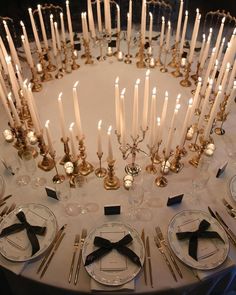 the table is set with many candles and place settings for dinner guests to sit at