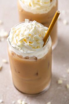 two glasses filled with ice cream and whipped cream on top of eachother, sitting on a table