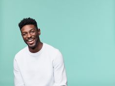 a man smiling while wearing a white sweater