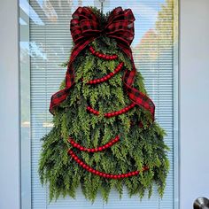 a christmas tree made out of evergreen branches and red berries hanging on the front door