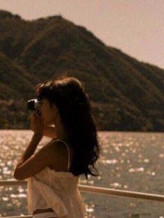 a woman on a boat looking out over the water with mountains in the background,