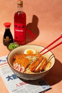 a bowl of ramen with chopsticks next to a bottle of sakeki