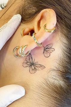 a woman with three butterfly tattoos on her behind the ear