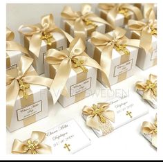 there are many small boxes with gold bows on them and tags attached to the packages