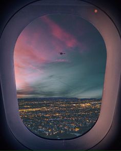 an airplane is flying over the city lights at night as it looks out into the distance