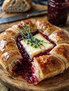 a croissant with cheese and jam on it is sitting on a wooden plate