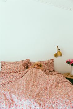 a woman laying in bed with her head on the pillow next to an alarm clock