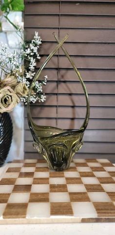 a glass vase sitting on top of a table next to a checkerboard board