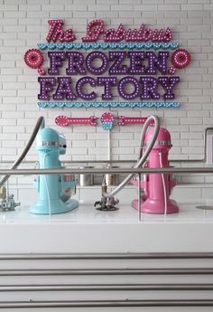 there is a sign that says frozen factory on the side of a building with pink and blue items