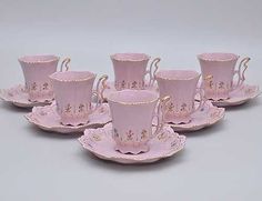 six pink coffee cups and saucers with gold trimmings on each one side