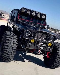 a large black truck with big tires and lights