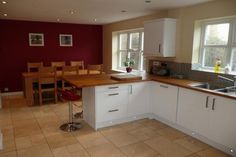 a kitchen with white cabinets and wooden counter tops next to a dining room table in front of a window