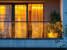 a balcony with lights on it and potted plants in the window