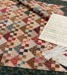 an old quilt is laying on the floor next to a piece of paper and scissors