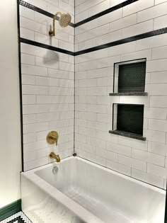 a white bath tub sitting under a window next to a tiled wall and flooring