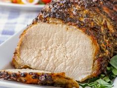 a large piece of meat sitting on top of a white plate next to some vegetables