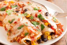 a white plate topped with enchiladas covered in cheese and black olives