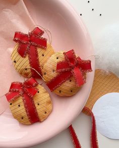 three wrapped cookies on a pink plate with red ribbon around the edges and two are sitting next to each other