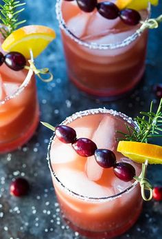 three glasses filled with drinks and garnished with lemons, cranberries, and rosemary