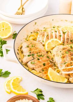 chicken with lemons and parsley in a skillet on a white counter top