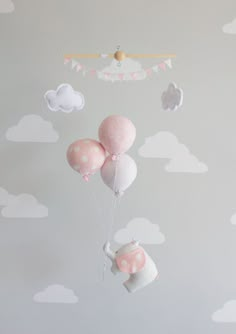 a baby crib with pink and white balloons floating in the sky above it is a cloud wall decal