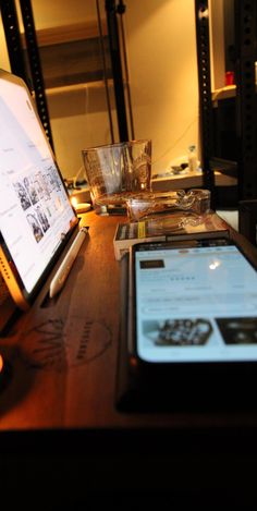 a laptop computer sitting on top of a wooden desk next to a glass bowl filled with water