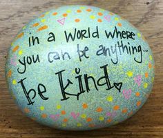 a painted rock that says, in a world where you can be anything be kind