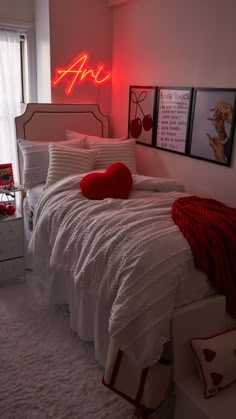 a bedroom with white bedding, red pillows and pictures on the wall above it