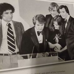 an old black and white photo of four men in suits standing behind a glass case