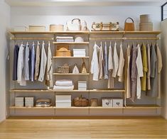 an organized closet with clothes, baskets and other items on shelves in the center of the room