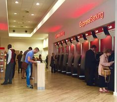 people are standing in line at the atm machine and checking their cell phones for cash