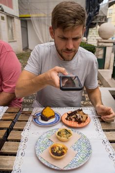 a man sitting at a table with plates of food and a camera in front of him