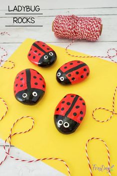 four ladybug rocks sitting on top of a yellow piece of paper next to twine