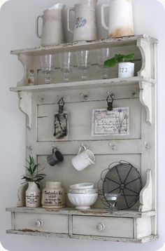 an old hutch is used as a shelf for kitchen utensils and mugs