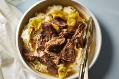 a white bowl filled with meat and mashed potatoes on top of a blue table cloth