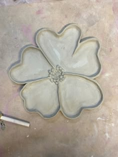 a white flower shaped dish sitting on top of a table next to a pencil and paper