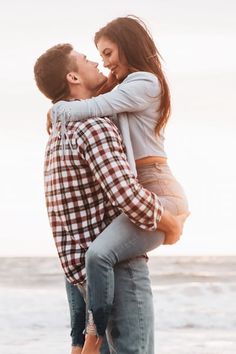 a man holding a woman on the beach