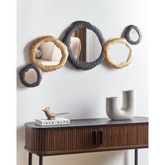 three circular mirrors mounted on the wall above a console