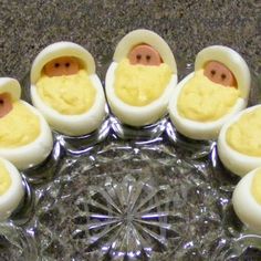 an egg tray filled with deviled eggs topped with small baby faces in the middle