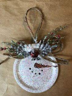 a snowman ornament hanging from a string on a piece of brown paper