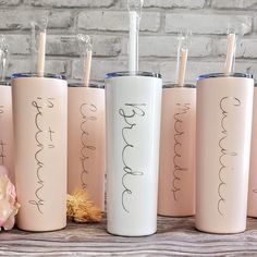 five pink tumbles with writing on them are lined up in front of a brick wall