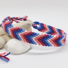 two bracelets with red, white and blue designs on them next to some rocks