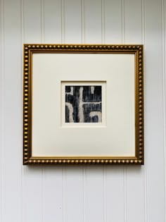 a framed photograph hanging on the wall next to a white and gold striped wallpaper