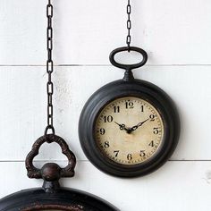 an old clock hanging on the wall next to a chain with a bell attached,