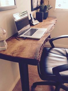 a laptop computer sitting on top of a wooden desk next to a black leather chair