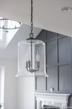 a chandelier hanging from the ceiling in a kitchen with white walls and cabinets